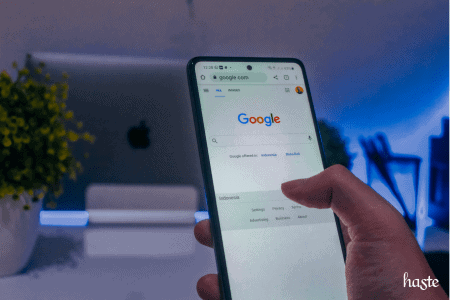 Mão segurando um celular que exibe a tela inicial do Google.